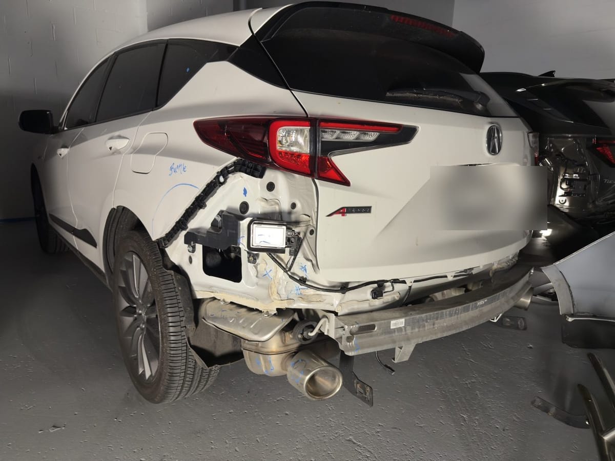Rear quarter panel and bumper collision damage on a white Acura RDX inside Exclusive Collision and Repair in Brooklyn, New York