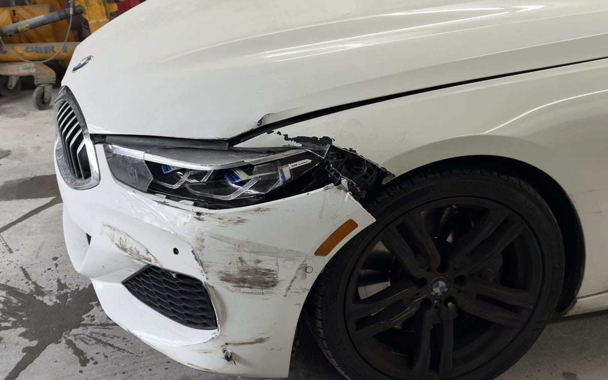 Front bumper and headlight collision damage on a white BMW 8 Series at Exclusive Collision and Repair in Brooklyn, New York