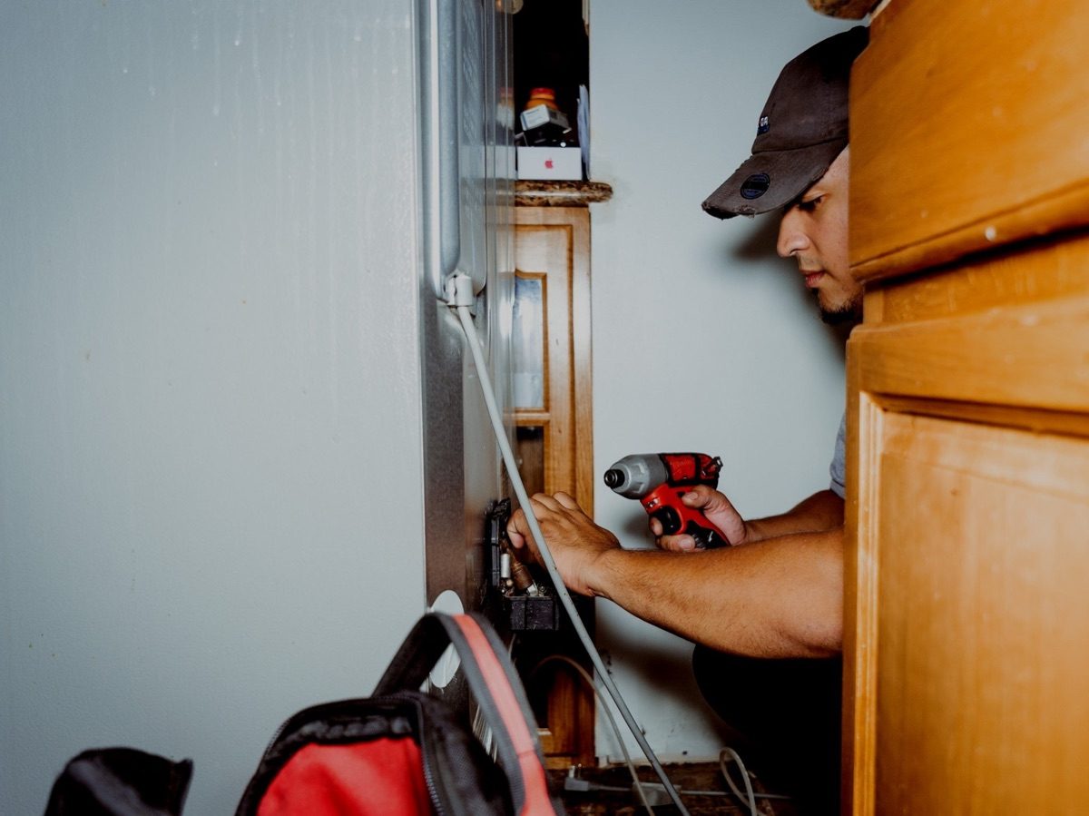 An appliance repair technician working on an open control panel