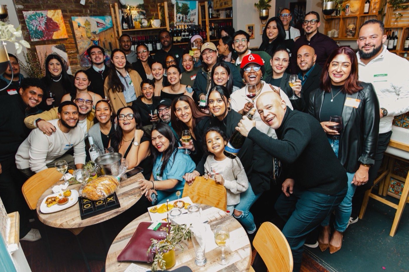 A packed Colado Latino Network gathering at a Baltimore wine bar, dozens of Latino entrepreneurs and creatives crowded around tables of food and wine