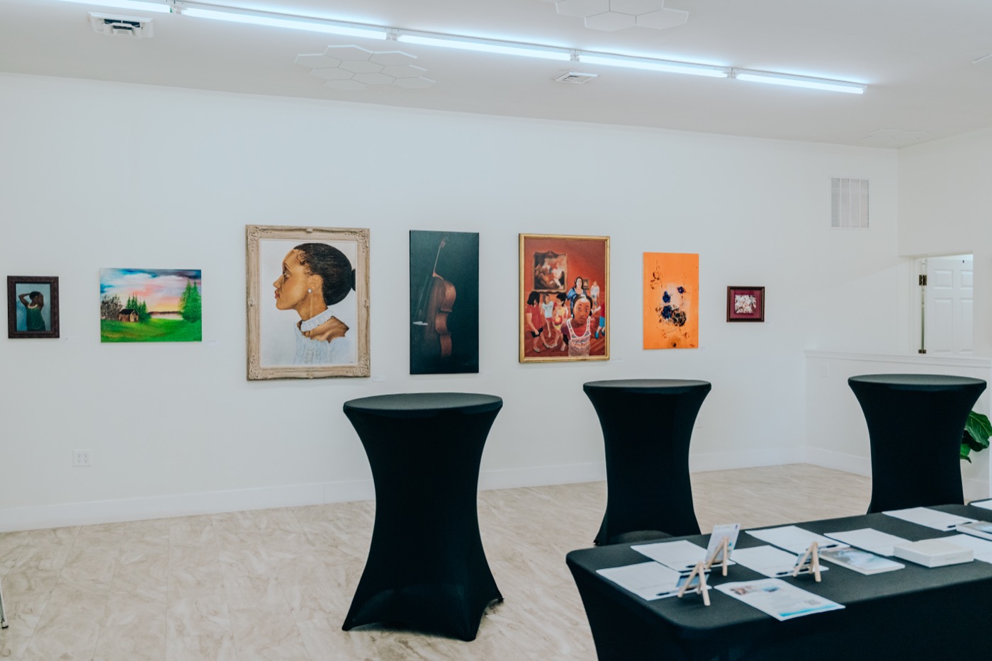 An art exhibit set up inside Studio 87 with framed paintings on the wall and cocktail tables on the floor, a non-wedding booking the six-part engine is built to fill