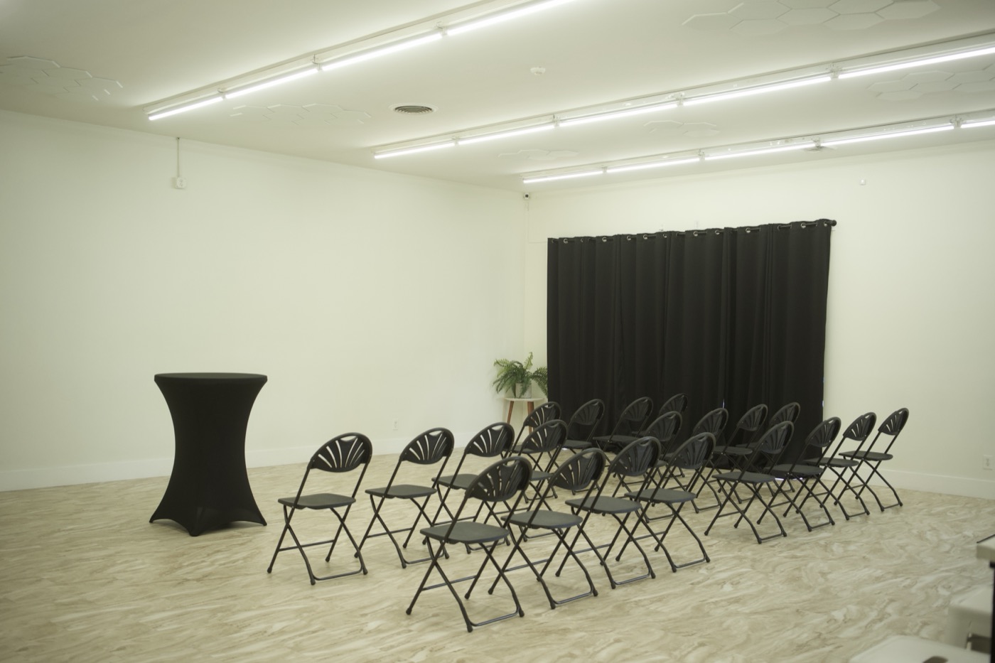 The empty Studio 87 room set with rows of black folding chairs facing a black curtain backdrop, the space this wedding venue marketing engine was built to fill