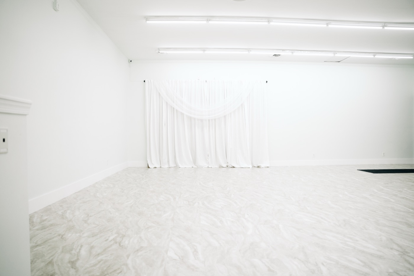 The empty Studio 87 room with a white draped backdrop against the wall, the blank canvas a wedding venue marketing plan is built to fill