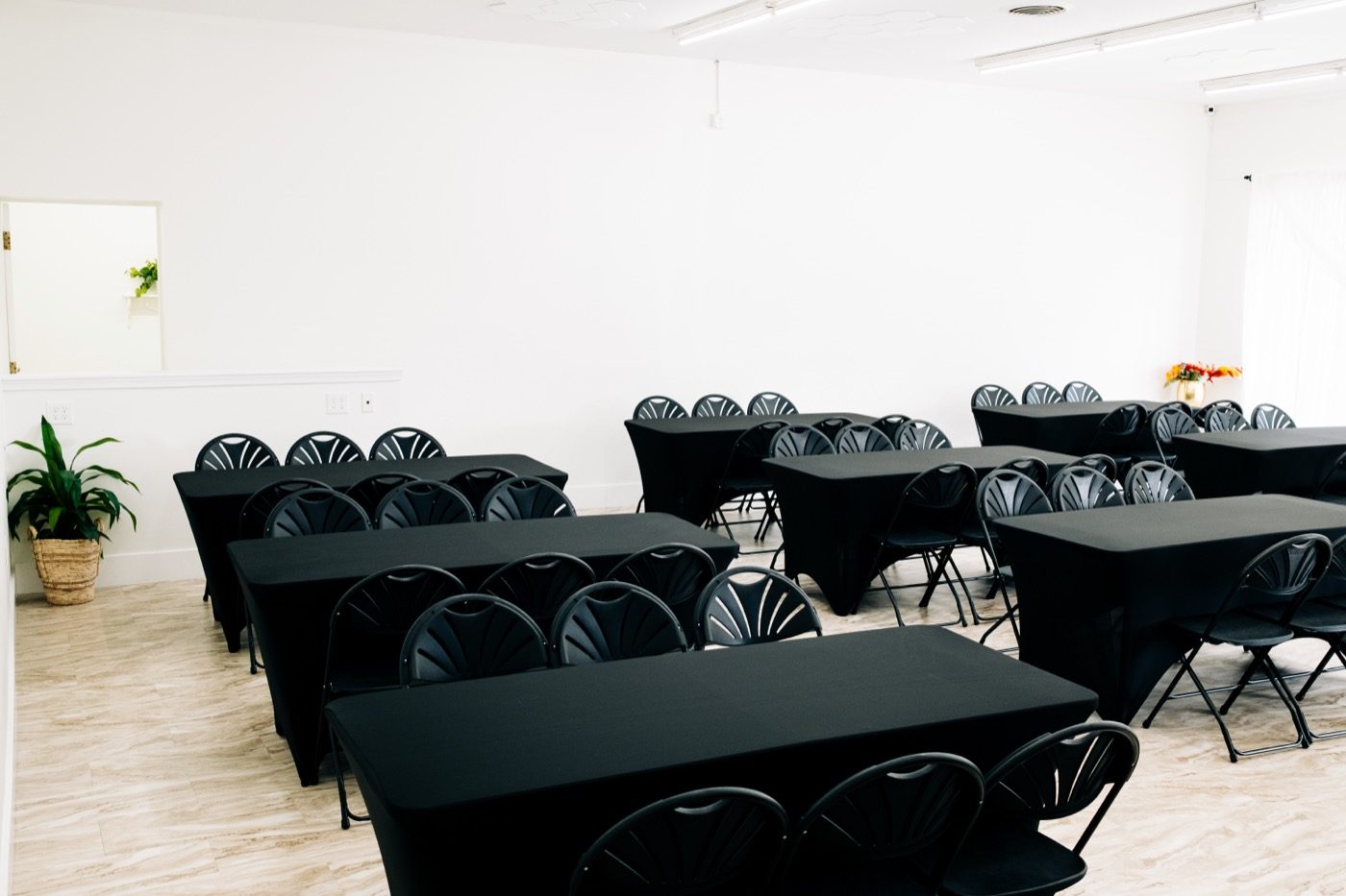 Studio 87's main room set classroom-style with black-linen tables and matching fan-back folding chairs, hexagon ceiling panels and a marbled floor visible, the flip between events that gives an event venue its best social media footage