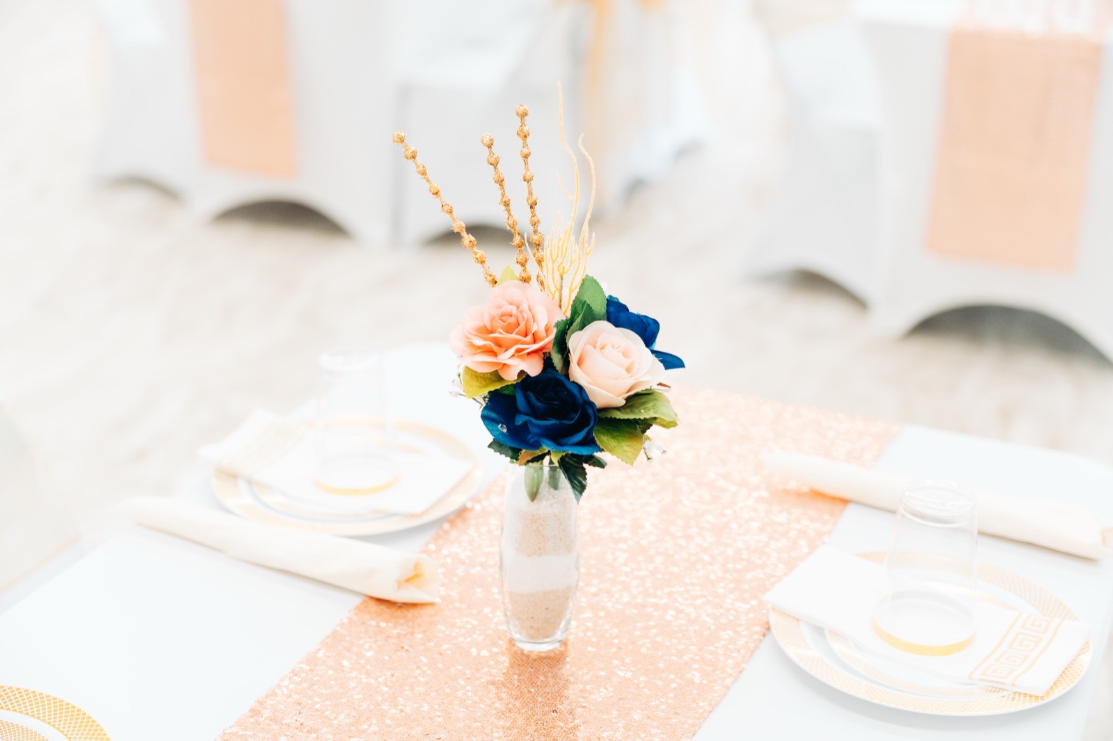 A blush and navy rose centerpiece on a rose-gold sequin runner at a Studio 87 wedding reception, the kind of detail shot a wedding venue gallery is built on