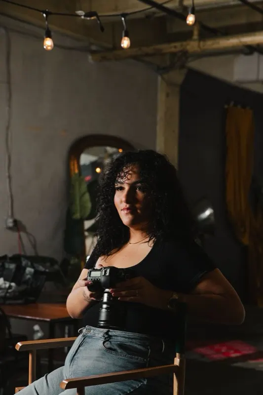 Amy of Create With Amy, a Baltimore-area photographer and creative director, holding her camera in a studio